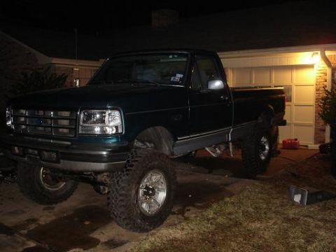 1996 Ford F-150 - This lifted 1996 Ford F-150 pickup truck is parked in front of a garage.