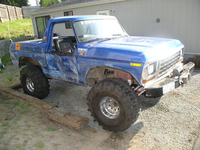 Blue lifted Ford Bronco on large mud tires parked on gravel