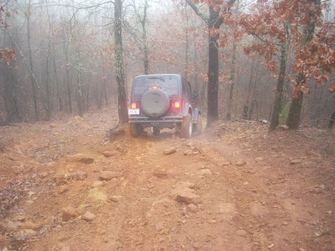 1992 Ford Bronco - A Jeep Wrangler navigates a challenging off-road path on a foggy day.