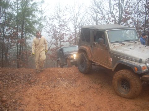 1992 Ford Bronco - Two Jeeps navigate a muddy trail during an off-road excursion.