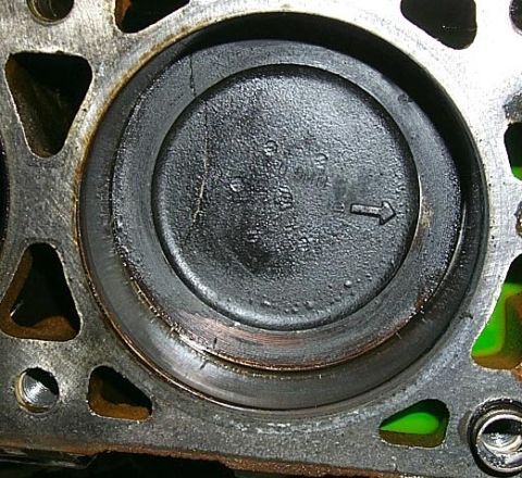 1988 Pontiac Fiero - Close-up view of an engine cylinder and piston, revealing wear and carbon deposits, with an arrow indicating direction.