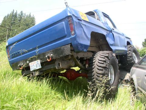 1979 Ford Bronco - This lifted 1979 Ford Bronco features oversized tires and a custom rear bumper, seen from a low angle in grassy terrain.