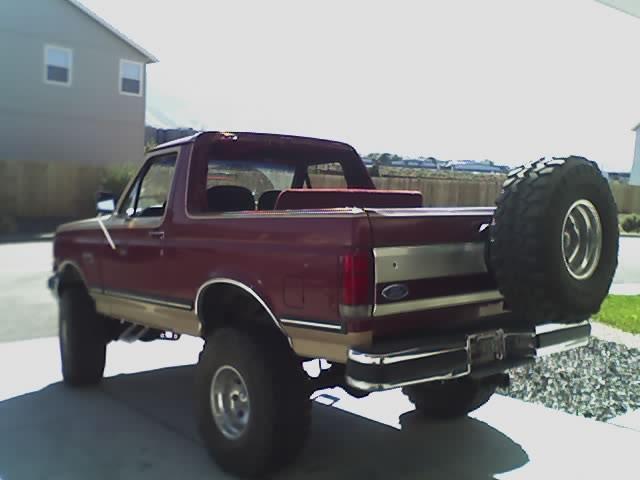 Lifted maroon Ford Bronco rear three-quarter with spare tire on tailgate