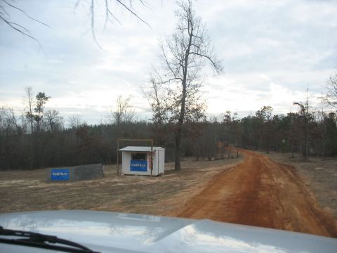 1978 Ford Bronco - View from inside a vehicle on a dirt road, passing a small shed with 'FABTECH' signage.