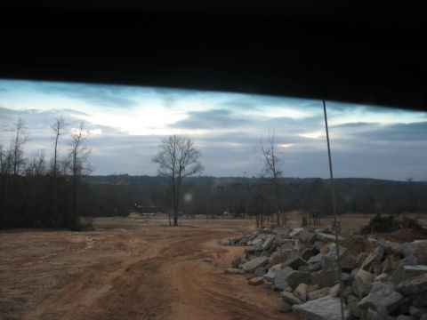 1978 Ford Bronco - A view of a rural landscape with a dirt road and scattered rocks, under an overcast sky.