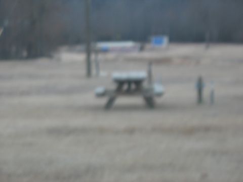 1978 Ford Bronco - A picnic table sits in a field with two figures standing in the distance.