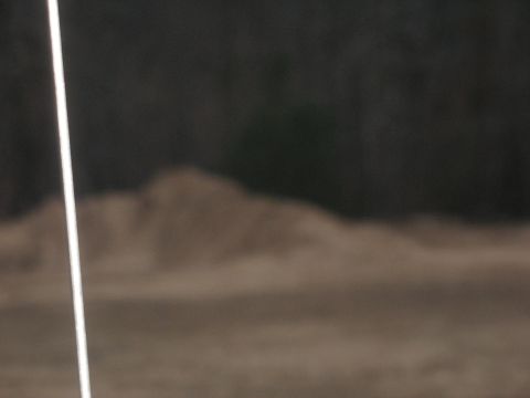 1978 Ford Bronco - A blurry scene with a dirt pile and trees, a white line is visible on the left side.
