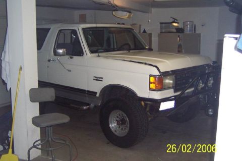 1990 Ford Bronco - This white Ford Bronco is parked inside a garage with a custom front bumper and off-road tires.