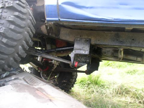 1979 Ford Bronco - Undercarriage view of a blue SUV with visible suspension and a large tire.
