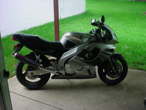 2004 Yamaha FZR600 - A silver Yamaha FZR600 motorcycle is parked outdoors on a concrete surface next to a grassy area.