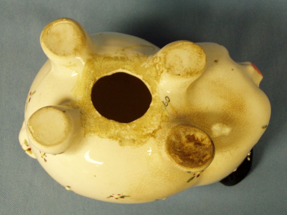 Underside of a ceramic piggy bank showing four feet and a round plug hole