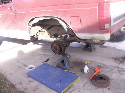 1986 Ford Bronco - Rear axle repair in progress on a red pickup truck, with tools laid out.