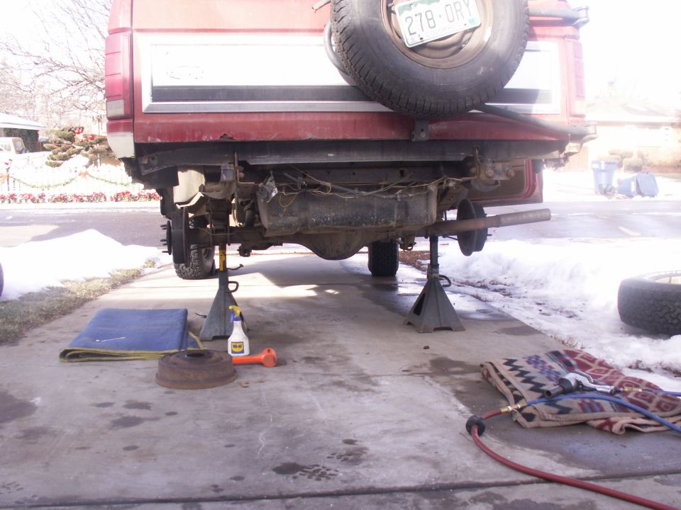 Red Ford Bronco rear raised on jack stands in snowy driveway