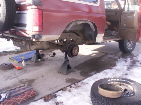 1986 Ford Bronco - Ford Bronco undergoing rear axle repair with wheels off and vehicle supported by jack stands.