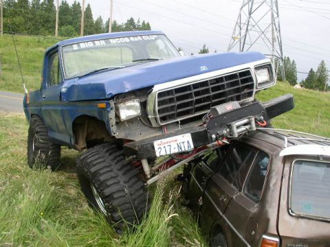1979 Ford Bronco - This lifted 1979 Ford Bronco is parked on top of a brown SUV, with its front bumper resting on the SUV's roof.