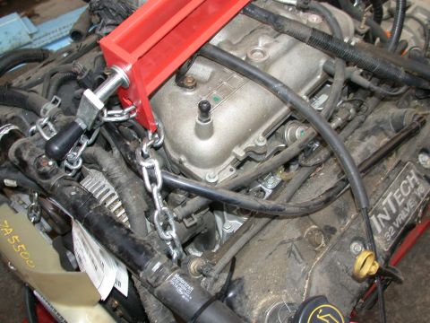1964 Ford Ranchero - An InTech 32 Valve V8 engine is supported by a red engine hoist and chains, ready for installation or removal.