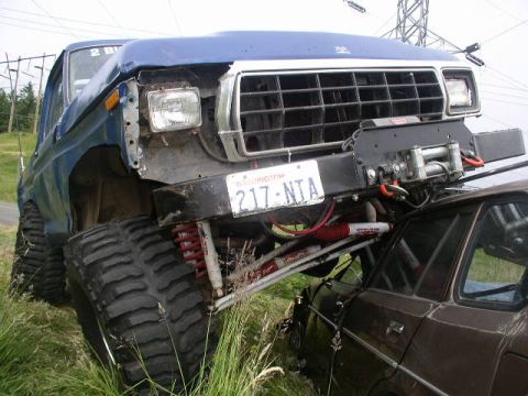1979 Ford Bronco - A modified 1979 Ford Bronco is shown with its front end angled towards the camera, resting on another vehicle.