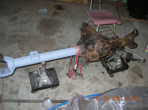 1991 Ford F-150 - A rusty differential axle assembly is supported by jack stands in a garage setting.