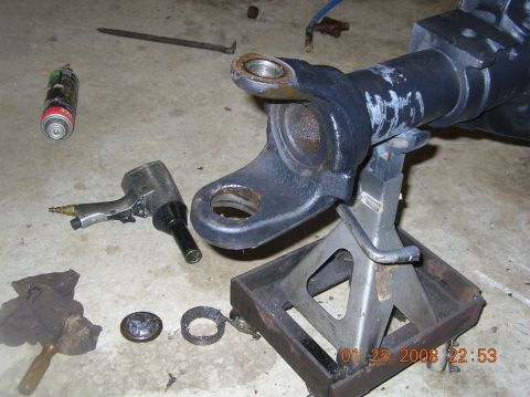 1991 Ford F-150 - A close-up of a Dana 60 axle housing, supported by jack stands, with various tools and disassembled parts on the floor.