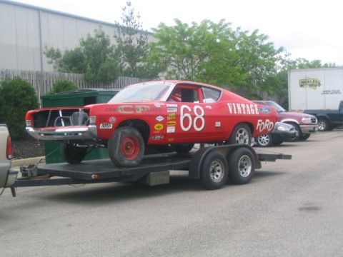 1968 Ford Torino - A red 1968 Ford Torino race car, number 68, is seen on a trailer with other vehicles in the background.