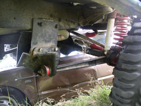 1979 Ford Bronco - Custom suspension parts are visible on an off-road vehicle, with a brown car in the background.