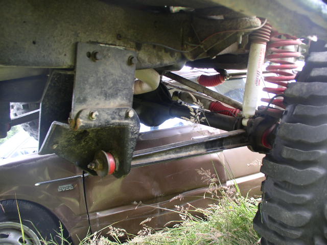 Underbody view of fabricated link bracket, radius arm and red coil springs on a lifted 4x4