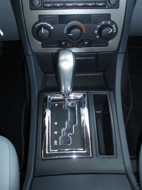 2007 Chrysler 300 - The center console of a car features a chrome-trimmed gear shifter and climate control knobs.