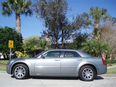 2007 Chrysler 300 - A silver Chrysler 300 sedan is parked on a street with palm trees and houses in the background.