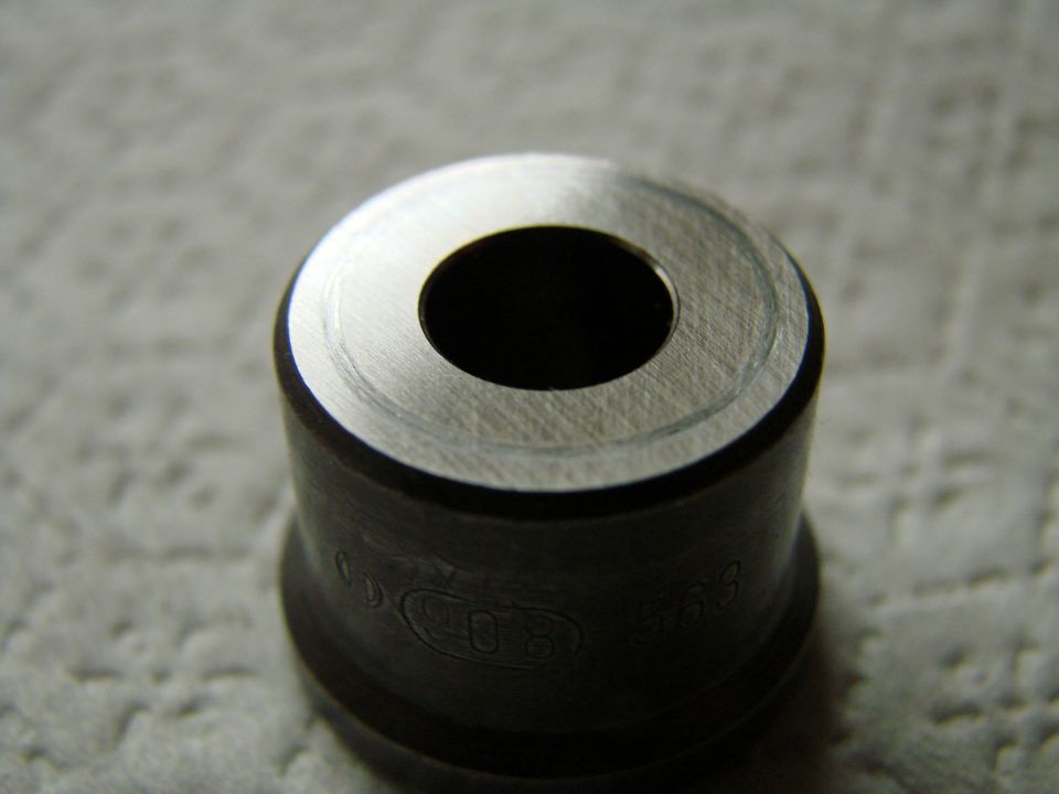 Close-up of a metal injector part with circular opening and visible markings