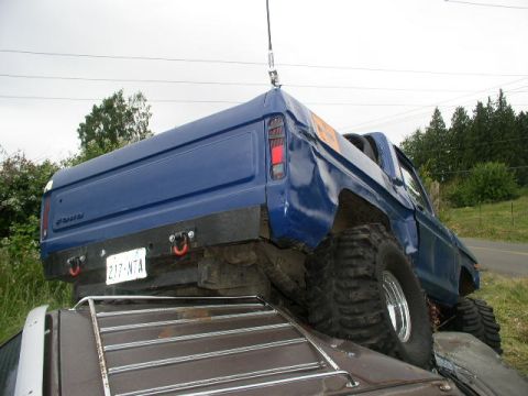1979 Ford Bronco - A blue 1978 Ford Bronco is shown from the rear, equipped with large off-road tires and a custom bumper.