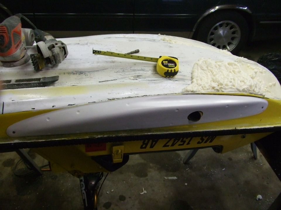 Yellow and white jet ski hull on trailer being repaired with fiberglass filler