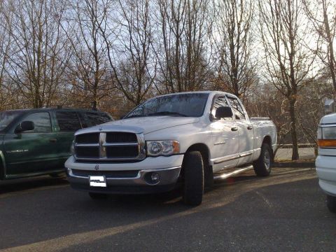1991 Ford Crown Victoria - A white Dodge Ram pickup truck is parked in a lot with trees in the background.