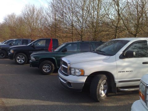 1991 Ford Crown Victoria - Several pickup trucks are parked in a row, with a white Dodge Ram 1500 prominently in the foreground.