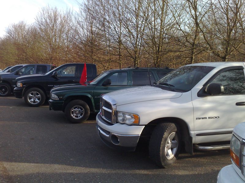 White Dodge Ram 1500 pickup truck front quarter view, parked in a line with other trucks