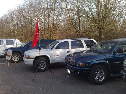 1991 Ford Crown Victoria - A line of Dodge Durango SUVs are parked outdoors, with a red flag planted in front of one.
