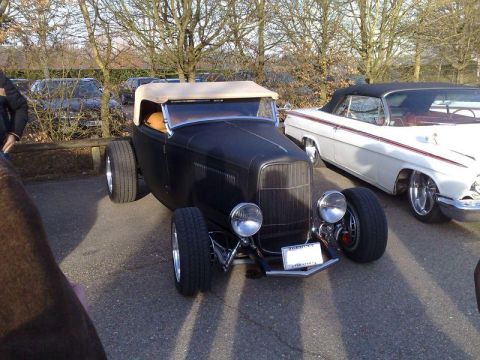 1991 Ford Crown Victoria - A black hot rod is parked next to a white convertible at an outdoor car show.