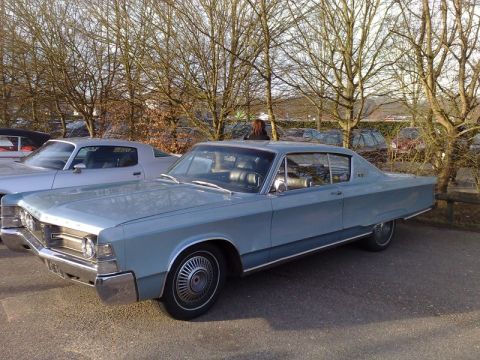1991 Ford Crown Victoria - A light blue sedan is parked in a lot with other vehicles and bare trees.