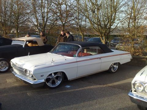 1991 Ford Crown Victoria - A classic white 1961 Chevrolet Impala convertible is parked outdoors with other vehicles and people nearby.