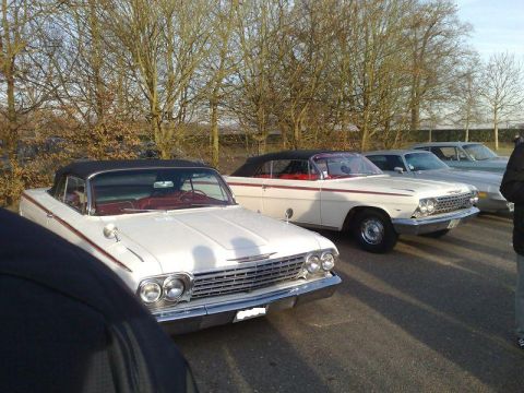 1991 Ford Crown Victoria - Two classic white Chevrolet convertibles with red interiors are parked at an outdoor event.