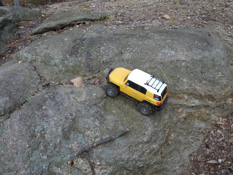 Yellow RC rock crawler with white roof on a rocky terrain