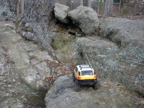 1996 Ford Bronco - A toy remote control SUV navigates a challenging rocky terrain with large boulders and trees.