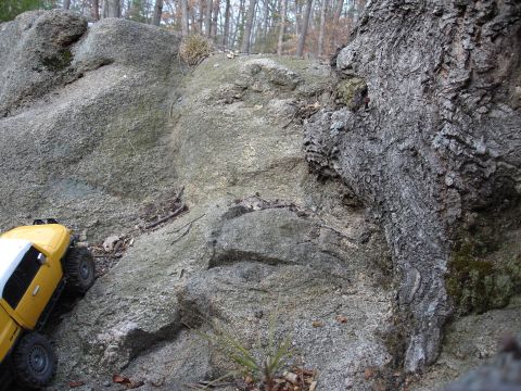 1996 Ford Bronco - A yellow RC rock crawler navigates a challenging rocky incline, dwarfed by natural terrain.
