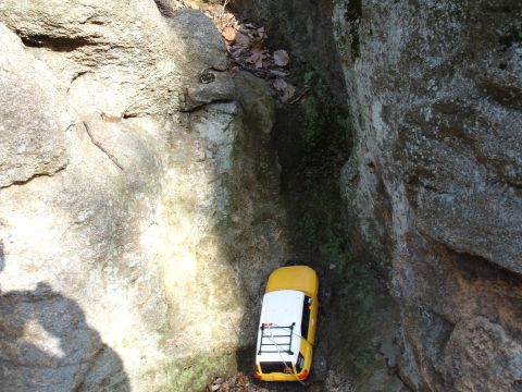 1996 Ford Bronco - A toy SUV is stuck in a tight spot between large rocks.