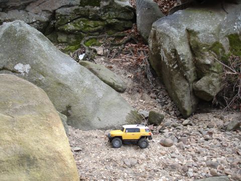 1996 Ford Bronco - A yellow toy FJ Cruiser navigates a rocky, outdoor environment.