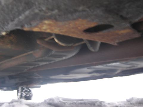 1991 Ford LTD Crown Victoria - The underside of a vehicle, including exhaust components and a tire, is visible against a snowy background.