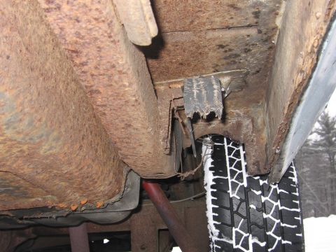 1991 Ford LTD Crown Victoria - The undercarriage of this vehicle shows significant rust and wear, with a tire covered in snow.