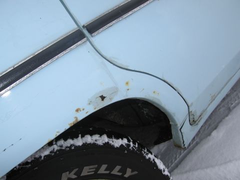 1991 Ford LTD Crown Victoria - Rust damage is visible on the fender of a light blue vehicle parked in the snow.