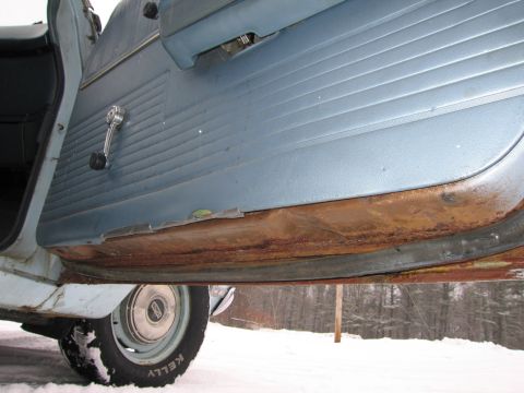 1991 Ford LTD Crown Victoria - The interior door panel and heavily rusted rocker panel of a vehicle are shown in this close-up shot.