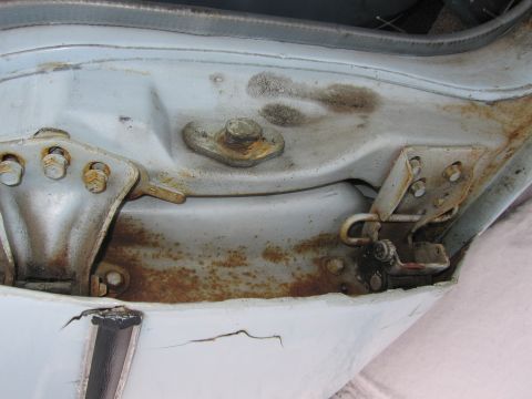 1991 Ford LTD Crown Victoria - Close-up of a car's door frame showing rusted hardware and paint damage.
