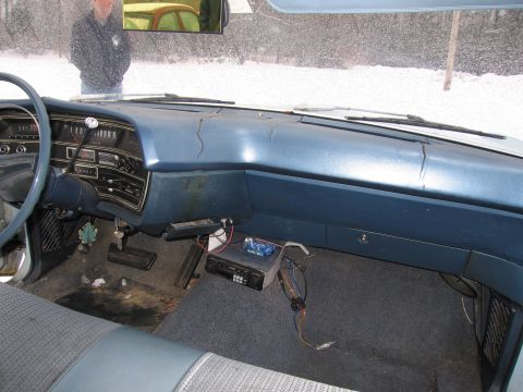 1991 Ford LTD Crown Victoria - The interior of an older vehicle shows a cracked dashboard and an aftermarket radio unit on the passenger side floor.